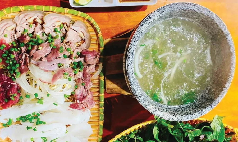 Stone bowl pho is served with many herbs to enhance the flavor
