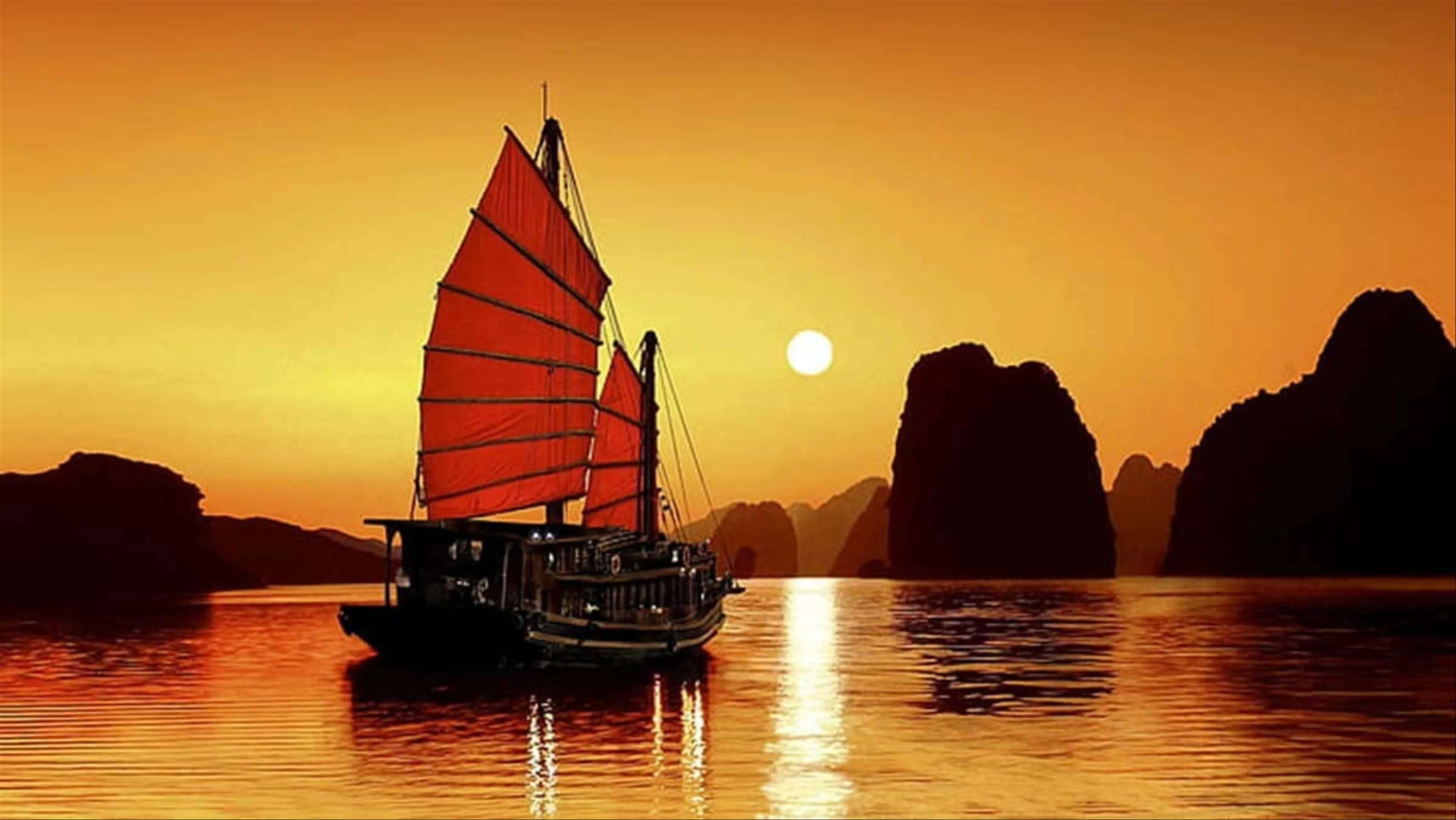 Traditional junk boat sailing through the limestone karsts of Ha Long Bay, Vietnam