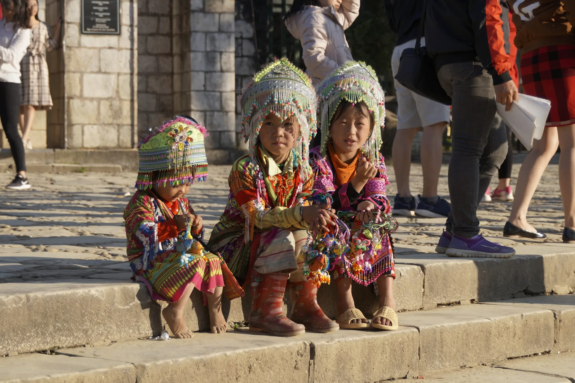 three girls from a Vietnamese ethnic minority tribe sitting on the stairs
